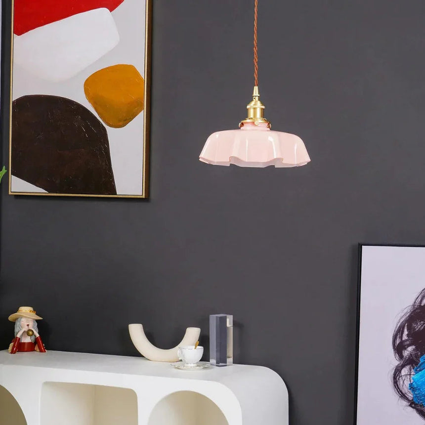 Pink scalloped shade on a dark wall above a white console and artwork