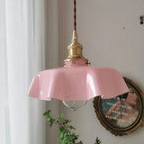 Pink scalloped shade beside a gilt oval frame and a trailing green plant