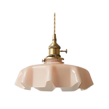 Pink scalloped glass shade with a brass top on a plain white background
