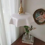 White scalloped shade hanging by a sheer curtain above a stack of books