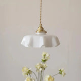 White scalloped shade hanging above a vase of small yellow flowers