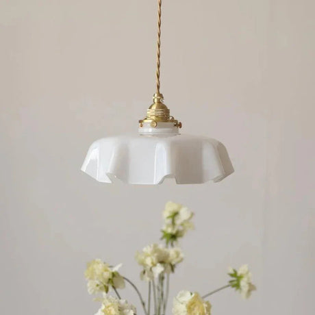 White scalloped shade hanging above a vase of small yellow flowers