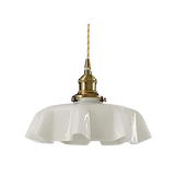 White scalloped glass shade with a brass top on a plain white background
