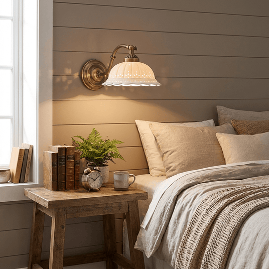 The sconce lit above a wood nightstand with a plant beside a bed with striped linens