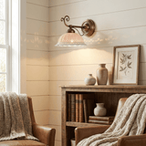The sconce on a shiplap wall above a wood bookcase between two armchairs