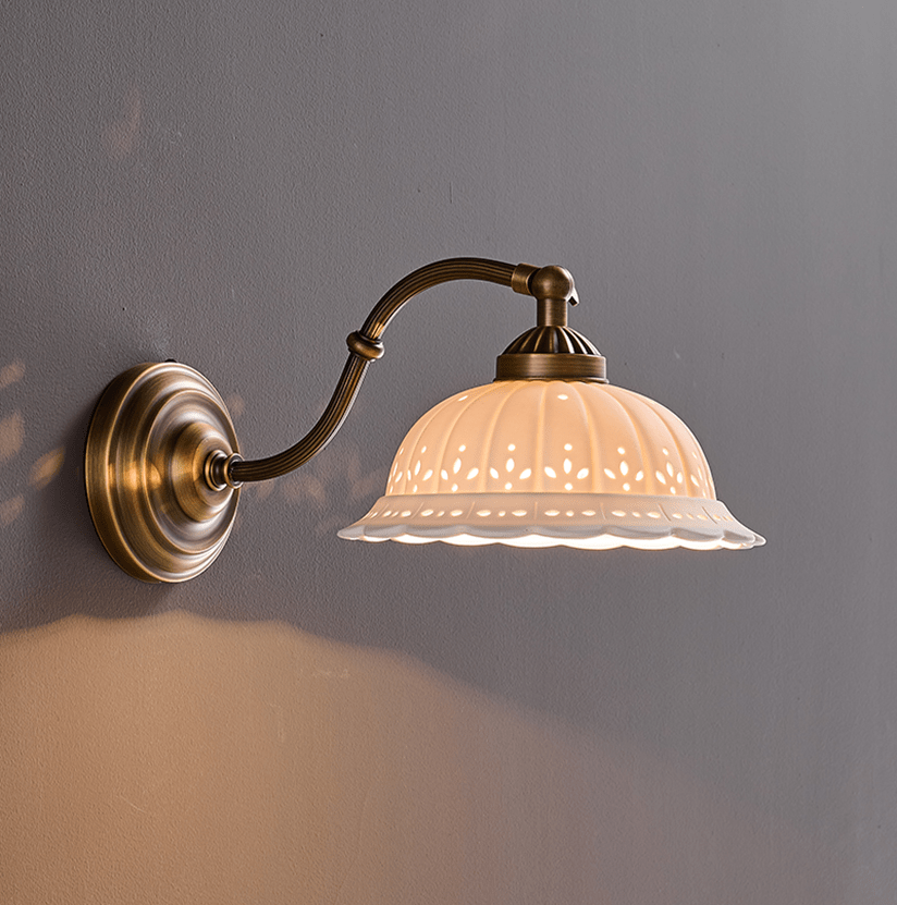 The curved arm style lit, the scalloped rim glowing on a gray wall