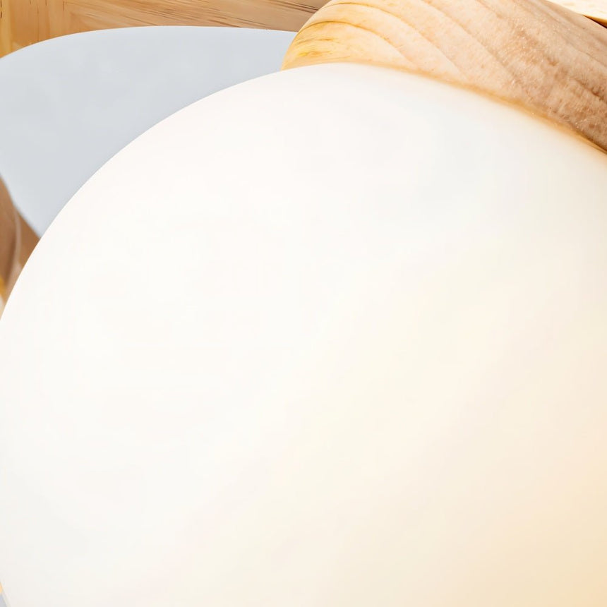 One white glass globe seen close where it meets the pale wood of the frame