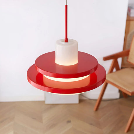 Red disc pendant above a wooden chair and a parquet floor