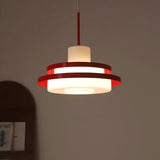 Red disc pendant seen against a warm pink wall