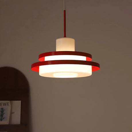 Red disc pendant seen against a warm pink wall