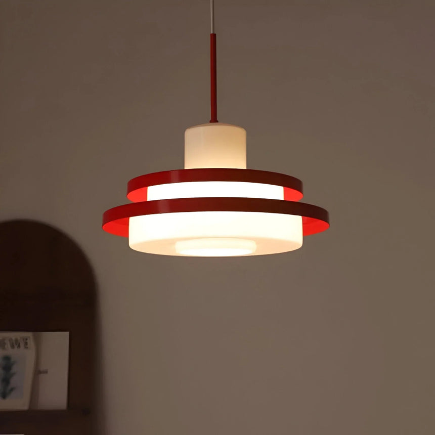 Red disc pendant seen against a warm pink wall