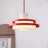 Red stacked disc pendant on a red cord against a pale wall