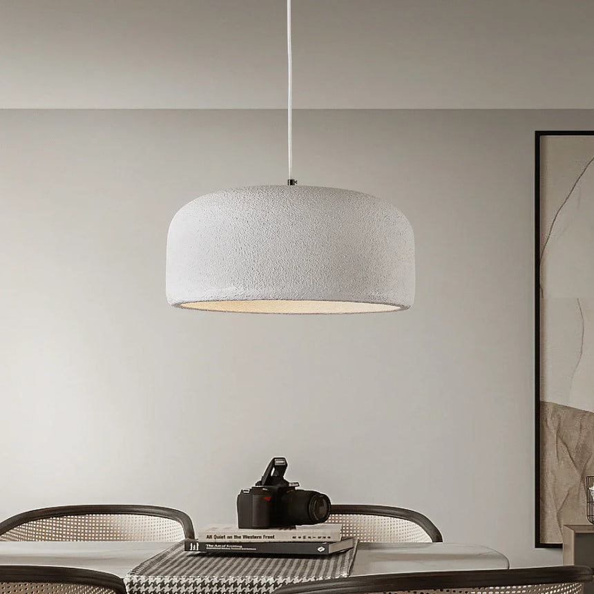 Textured dome pendant hung over a dining table in a pale room