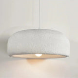 Scandinavian pendant lamp with a textured white dome shade lit above a table