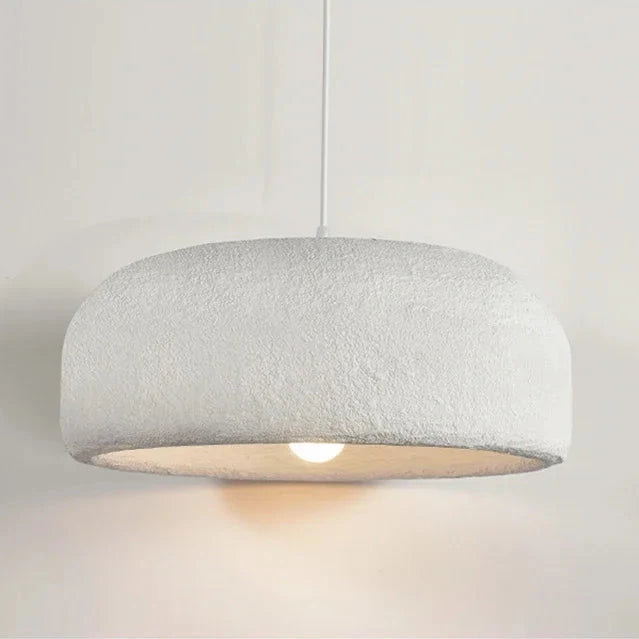 Scandinavian pendant lamp with a textured white dome shade lit above a table