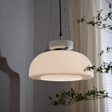 The cream dome lit in a corner beside a pale curtain and a green plant
