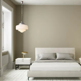 Opal shade hanging in a pale bedroom beside a made bed and a nightstand