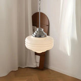 Chrome topped opal shade in front of a curved wooden panel and pale curtain