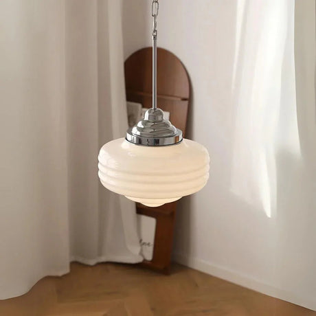 Chrome topped opal shade in front of a curved wooden panel and pale curtain