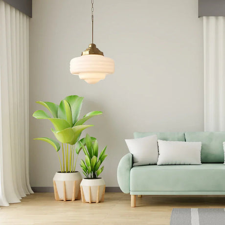 Opal shade lit in a living room with a green sofa and three potted plants