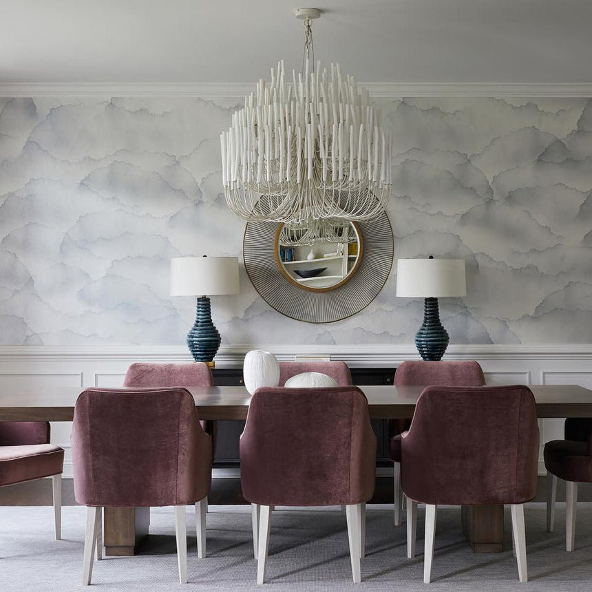 Chandelier lit above a dining table with a plaster wall behind it