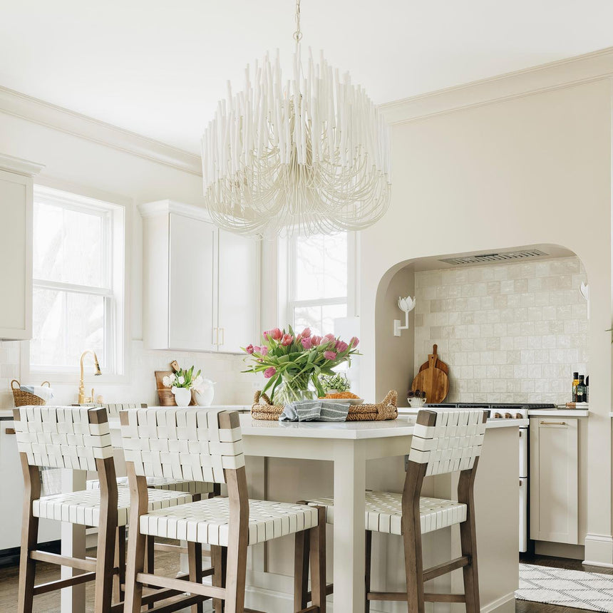 Chandelier lit above a kitchen island with stools and open shelving