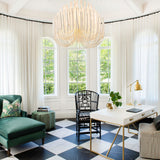 Chandelier lit in a room with a checkerboard floor and a green chaise