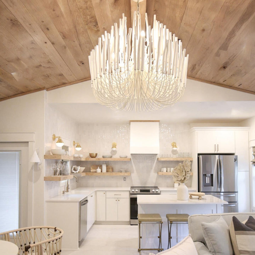 The fitting lit above a white kitchen with a timber plank ceiling