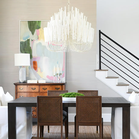 Chandelier lit above a dark dining table with cane back chairs
