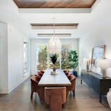 Chandelier lit above a long dining table with leather chairs around