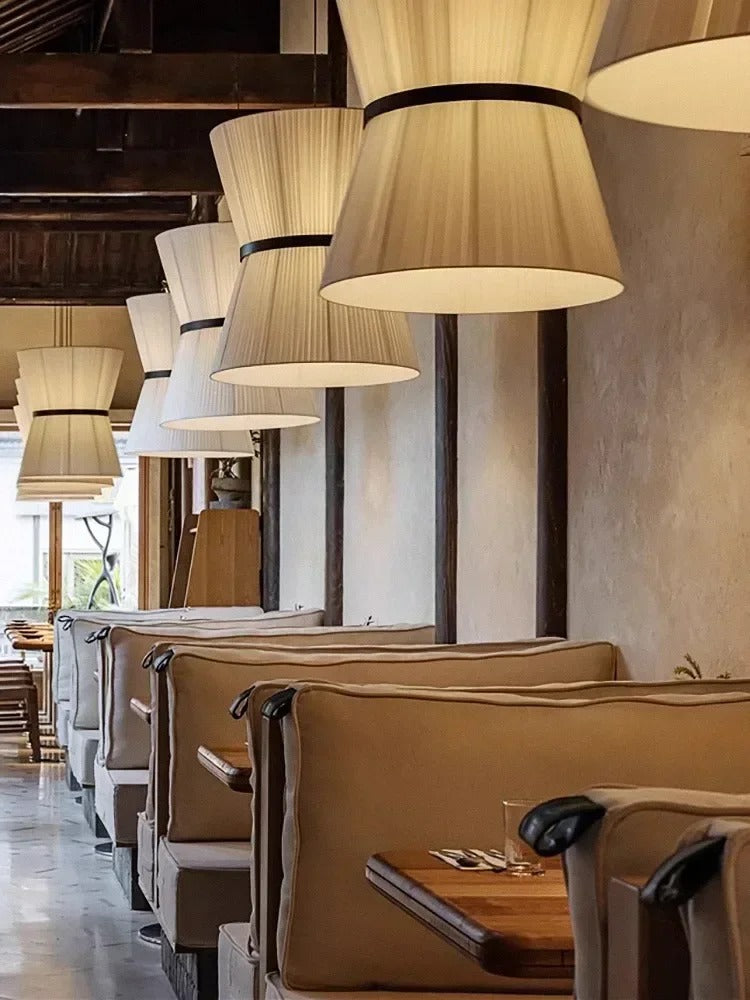 Sculptural pendant light with a knitted hourglass shade above a table