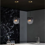 Two folded glass shades lit against a black marble wall above a counter