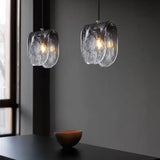 Two folded glass shades lit above a dark counter with a stone bowl