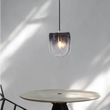 The folded glass shade lit above a round table in a sunlit corner