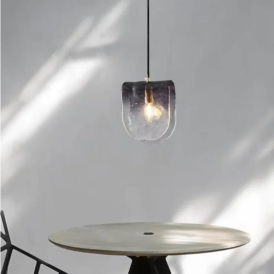 The folded glass shade lit above a round table in a sunlit corner
