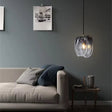 The folded glass shade lit above a sofa beside a framed artwork