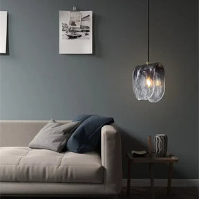 The folded glass shade lit above a sofa beside a framed artwork