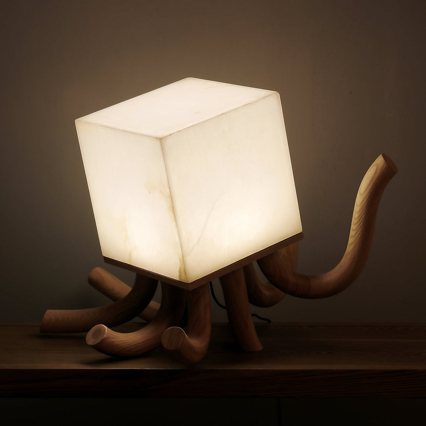 The alabaster cube of the sculptural table lamp lit and seen close