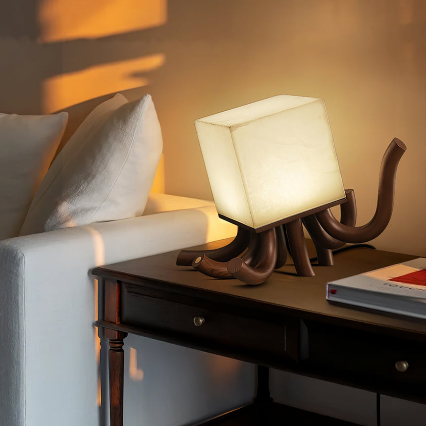 Sculptural table lamp lit on a dark console beside a sofa