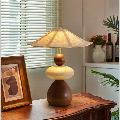 Sculptural table lamp lit on an antique console beside a framed print