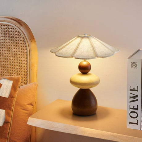 Sculptural table lamp lit on a pale shelf beside a standing book