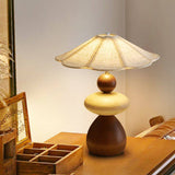 Sculptural table lamp lit on a wood desk beside a jewelry box