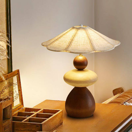 Sculptural table lamp lit on a wood desk beside a jewelry box