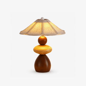 Sculptural table lamp with three stacked wood forms on a plain ground