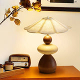 Sculptural table lamp lit on a wood table beside an old radio