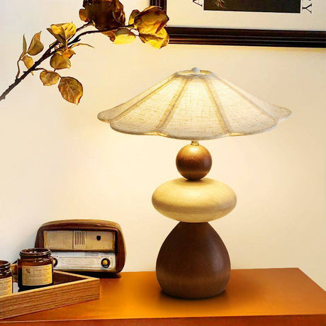 Sculptural table lamp lit on a wood table beside an old radio