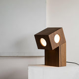 Front view of the teak lamp lit, the diffusers reading as two eyes