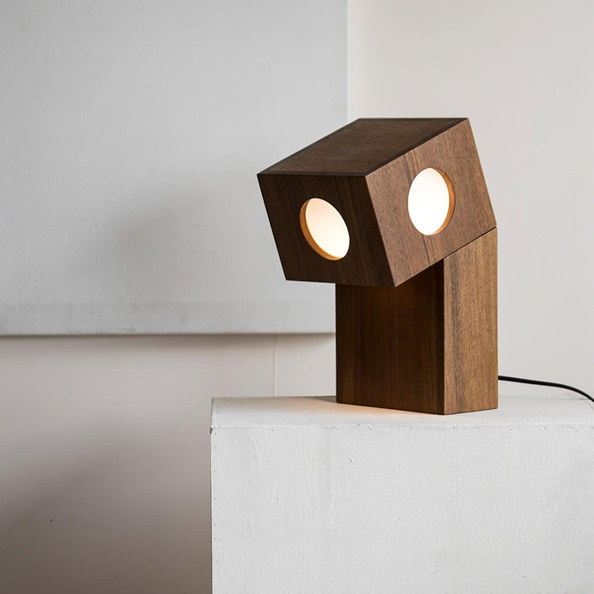 Teak block lamp lit on a white plinth, both diffusers glowing