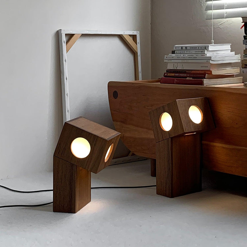 Teak lamps lit on the floor beside a low wood bench