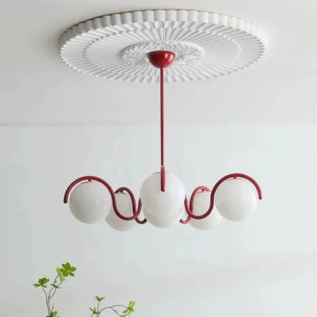 Red curved arms with opal globes under a molded white ceiling rose